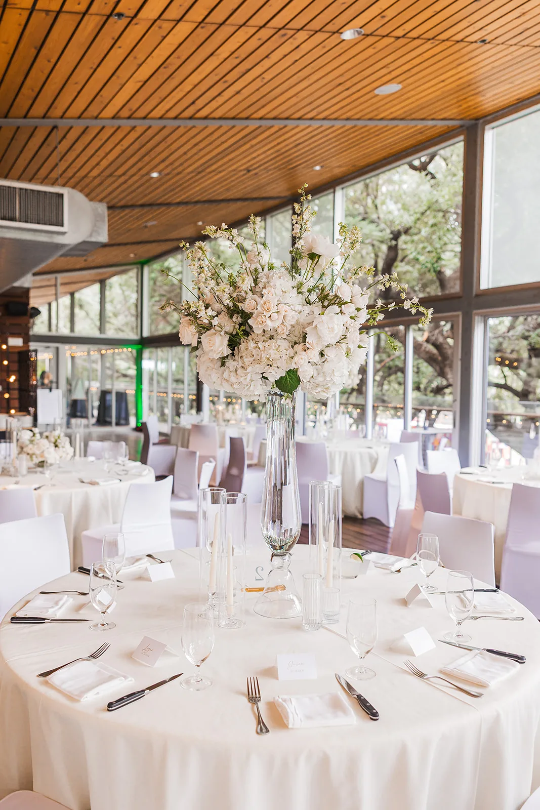 White floral reception centrepieces beneath a timber ceiling