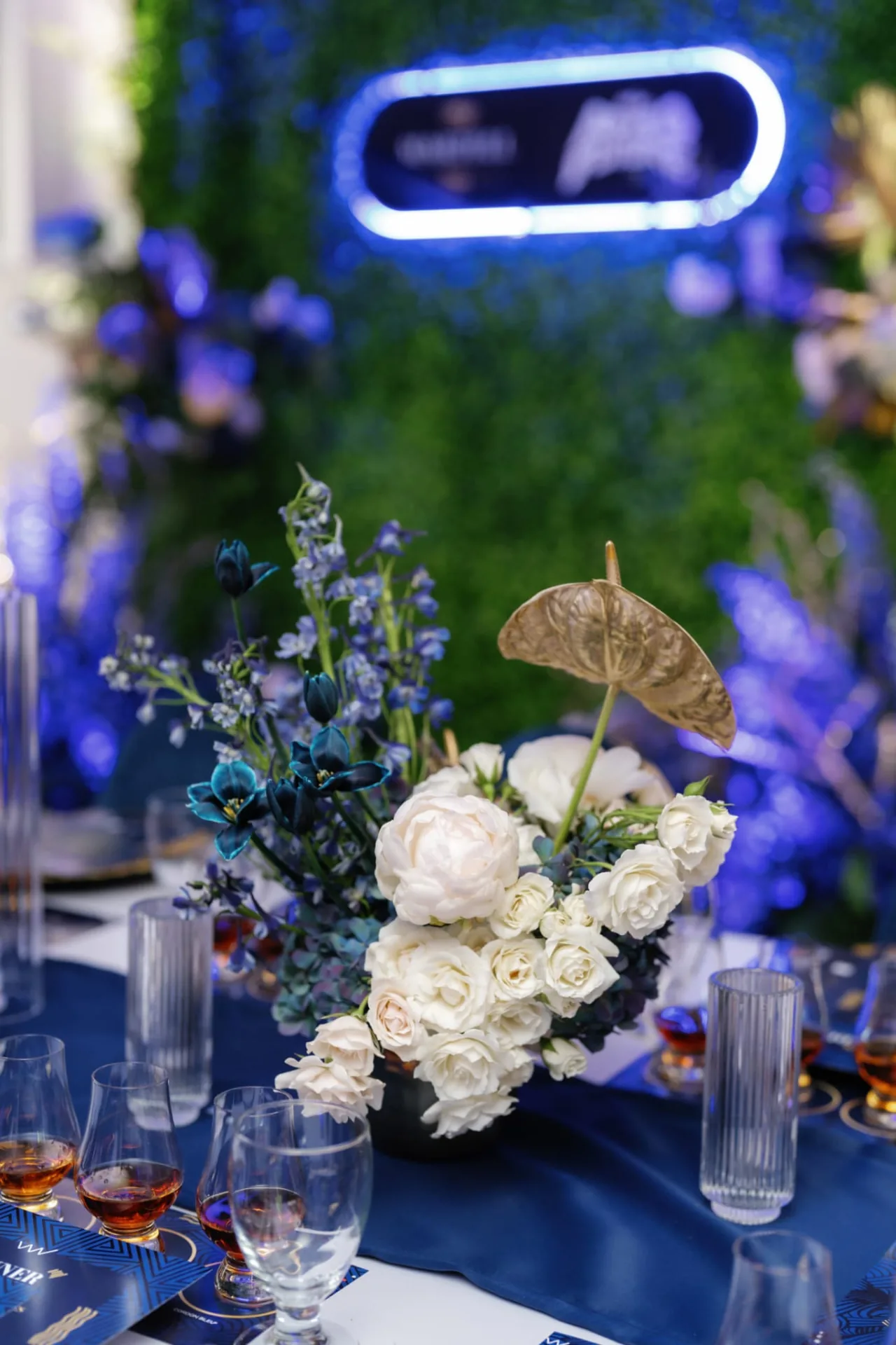 Blue-lit branded event table with florals — EVENT by OVA