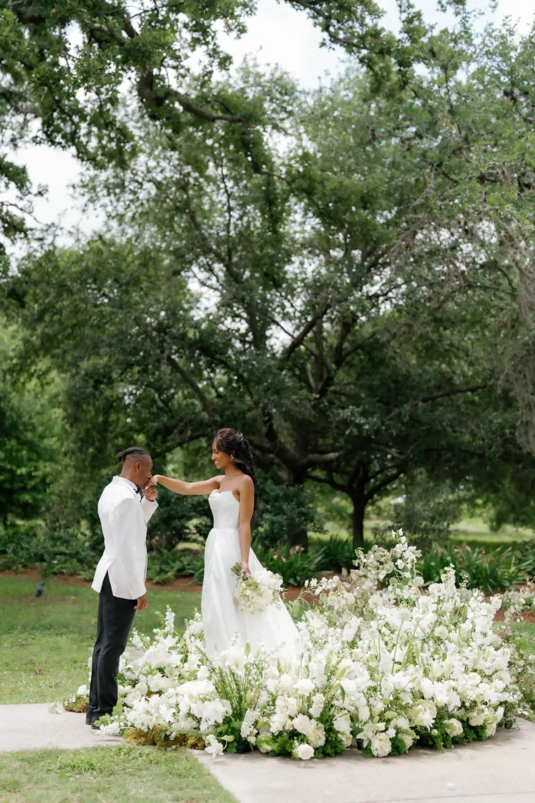 Couple beside a white floral meadow installation by EVENT by OVA