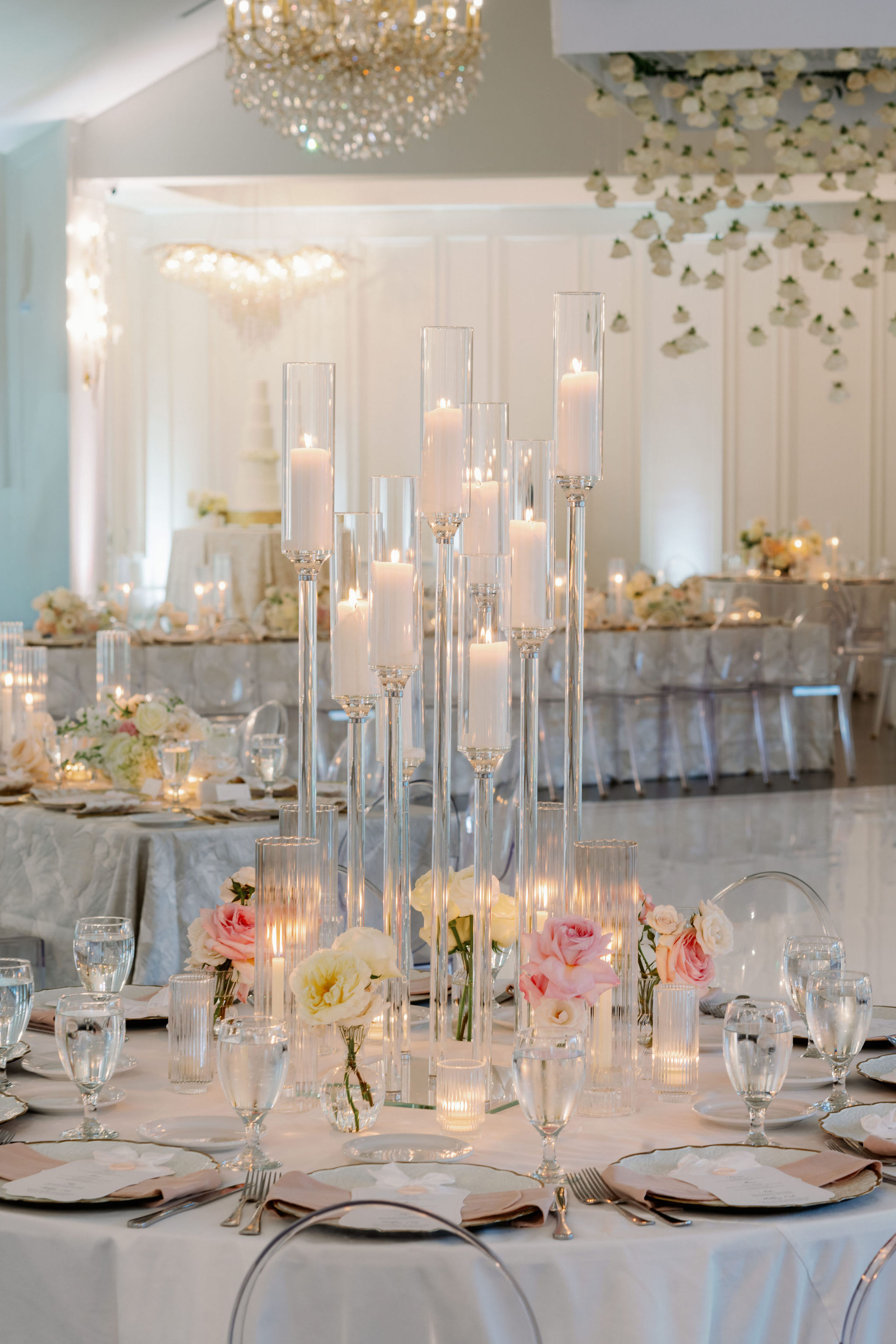 Tall glass hurricane candleholders and blush and ivory garden roses create an elegant reception centerpiece.