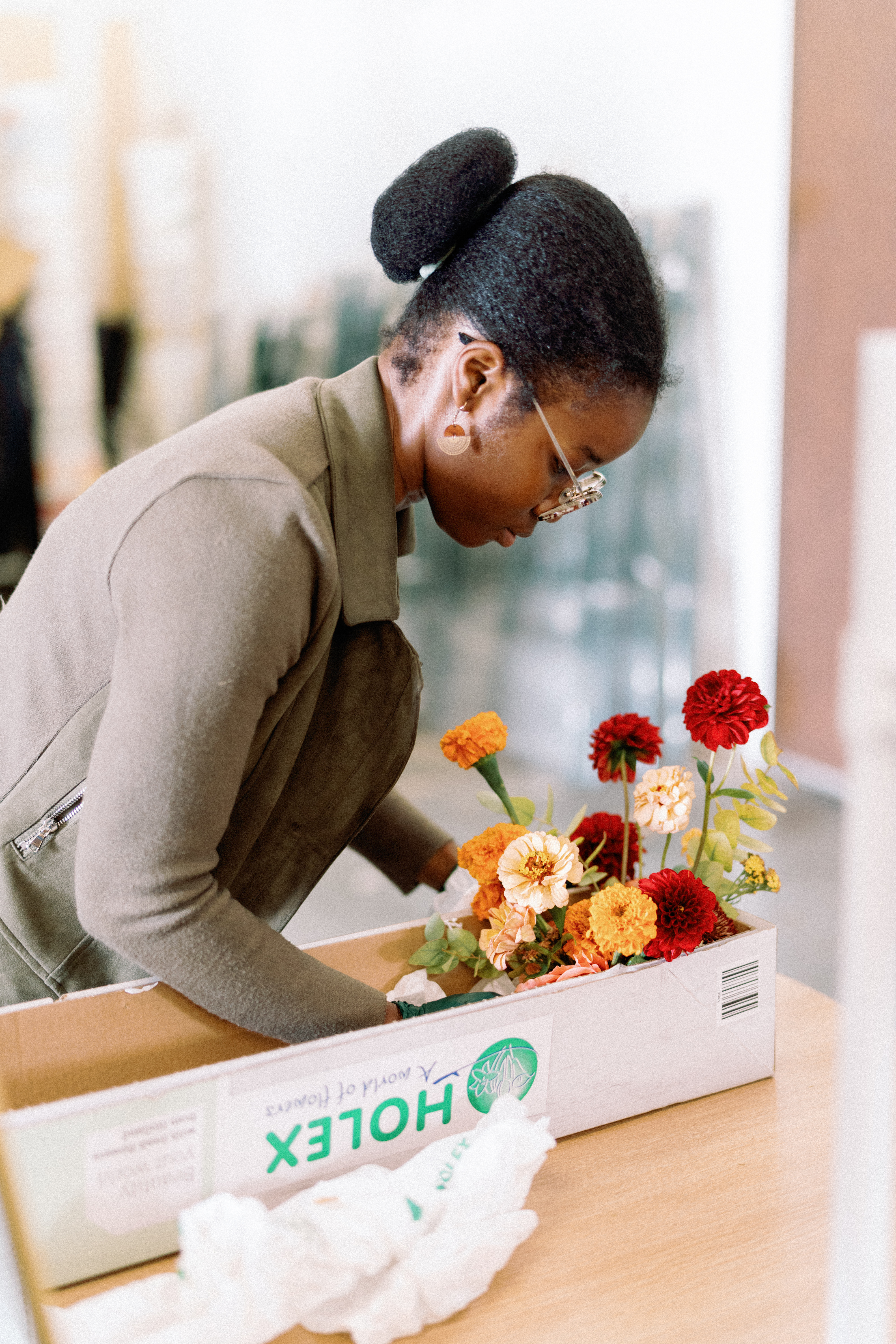 A floral designer inspects vibrant orange and peach blooms from a box during floral arrangement preparation.