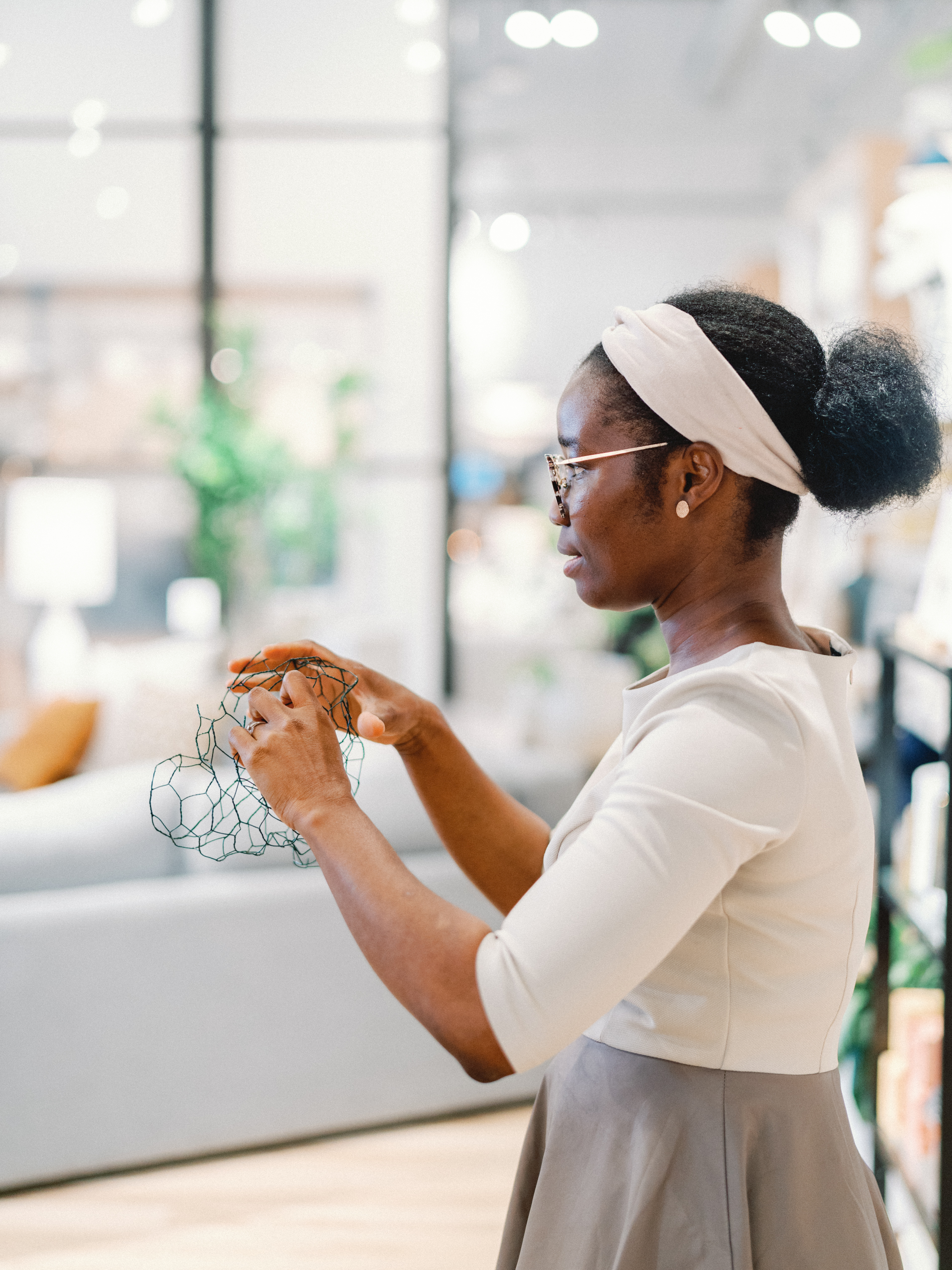 A woman shapes green floral wire mesh with her hands during an interactive arrangement workshop.