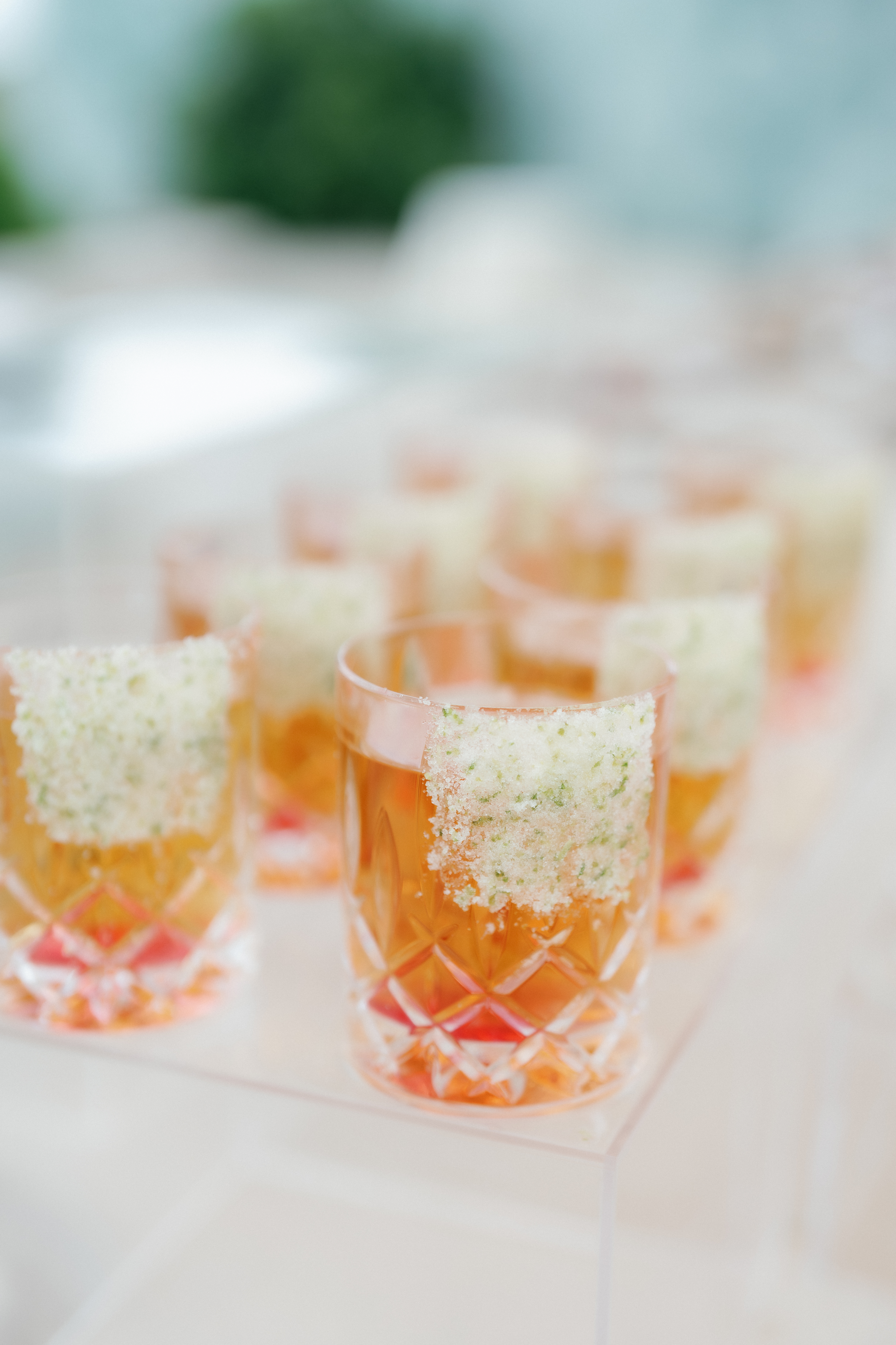 An amber cocktail in an ornate cut-crystal glass finished with a granulated citrus rim.