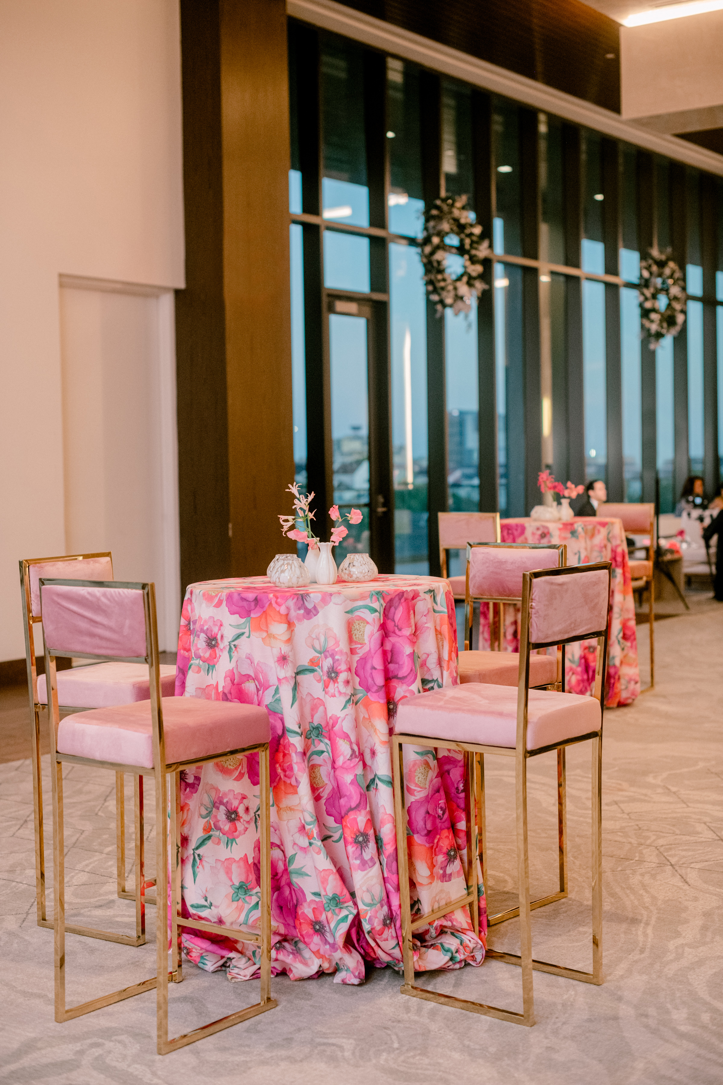 High cocktail table dressed in pink floral linen, paired with blush velvet gold barstools and delicate pink sweet peas.