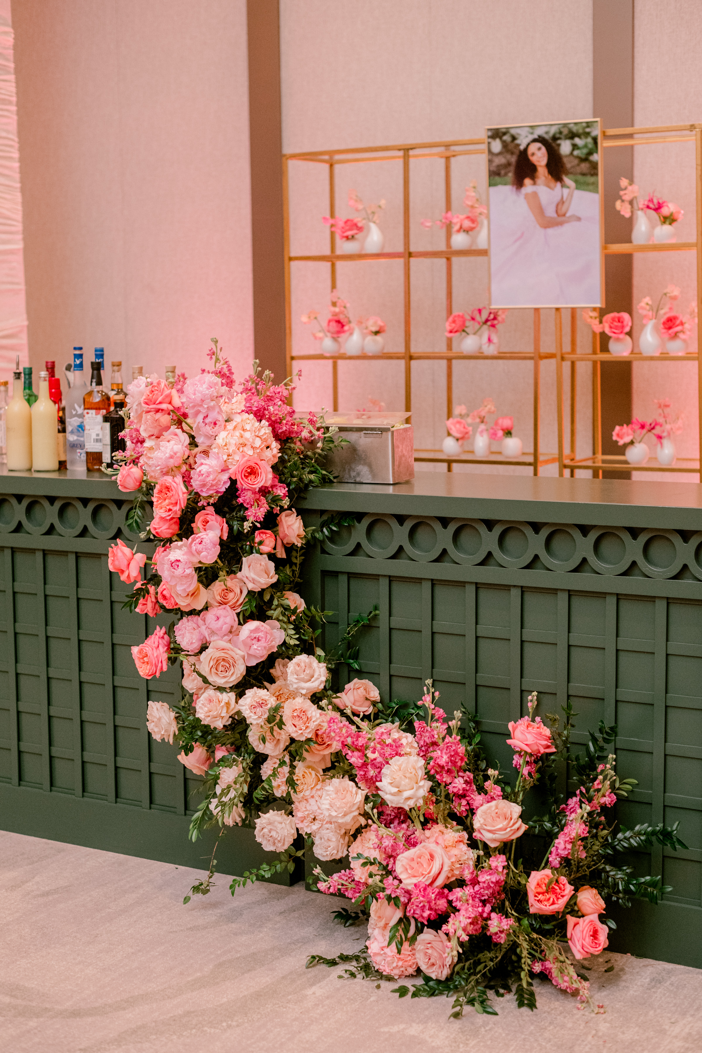 Lush pink and blush roses and peonies cascade down the side of a deep green custom event bar.