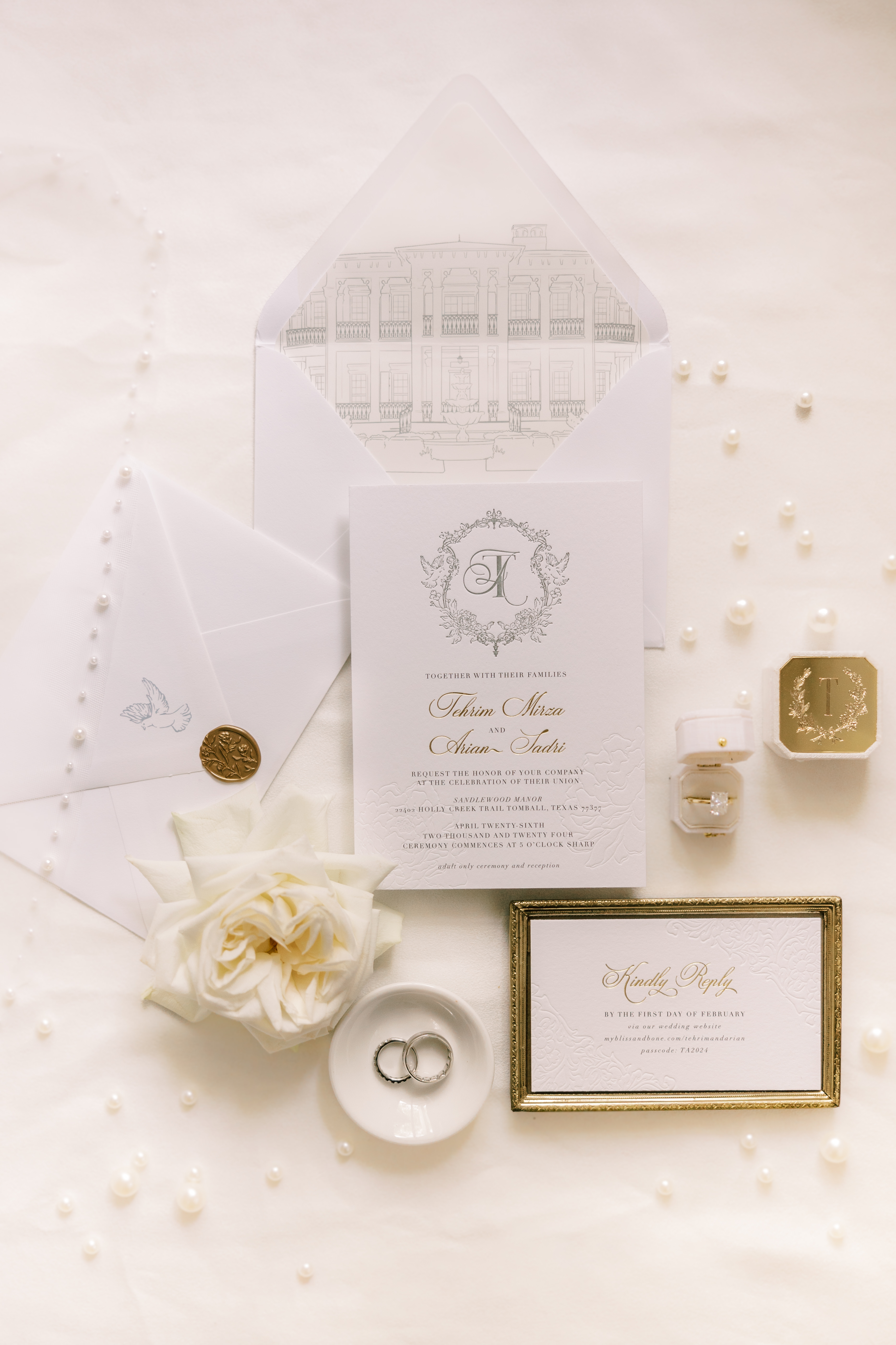 Elegant wedding invitation suite with an architectural envelope liner, gold lettering, rings in a ceramic dish, and a white rose.