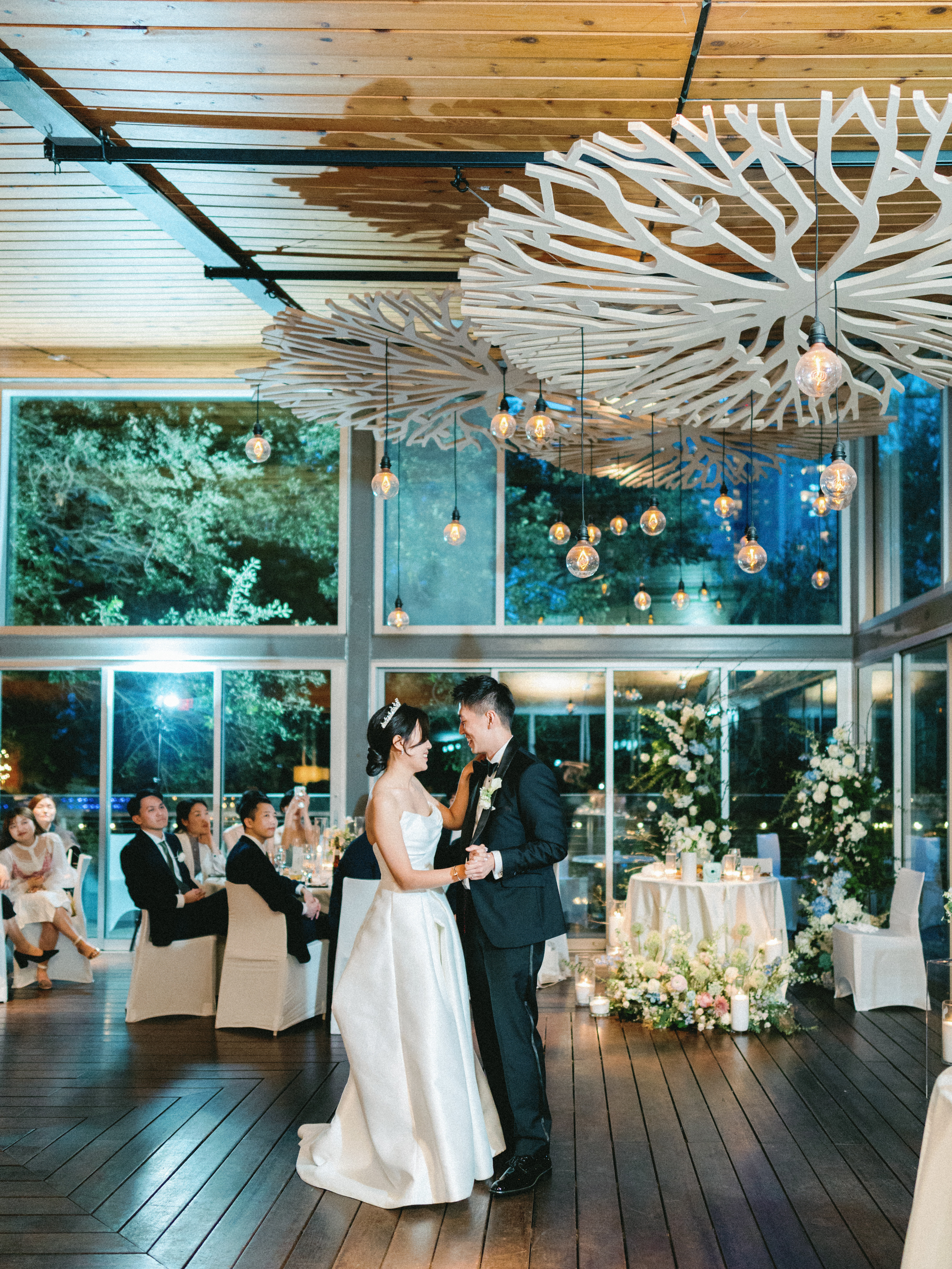 Bride and groom dancing under warm Edison pendant lights and an intricate sculpted ceiling canopy at their wedding reception.